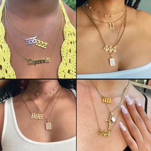 Close-up of stacked stainless steel necklaces with gothic number charms in gold and silver