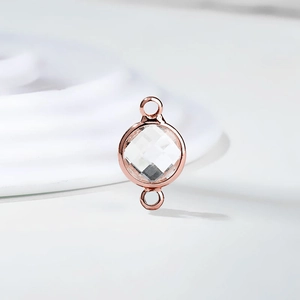 Macro view of a round rose gold connector with a clear birthstone for DIY jewelry