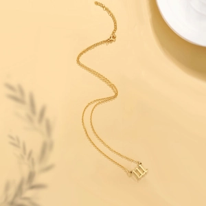 Detail of gold angel number 111 pendant on thin link chain with soft lighting