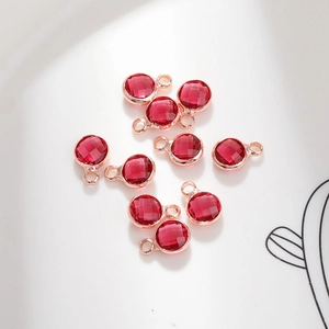 Close-up of nine 6mm round faceted red crystal pendants with rose gold metal frames