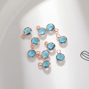 Macro shot of 6mm blue glass birthstone pendants with rose gold plated copper edges for DIY jewelry