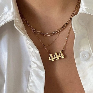 Detailed close-up of layered gold stainless steel necklace featuring a gothic 444 pendant