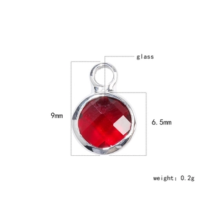 Macro detail of a 6.5mm red faceted glass birthstone charm with 9mm silver metal frame