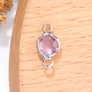 Macro-detail van een 6mm facetgeslepen roze geboortesteen met zilveren lussen voor DIY-sieraden