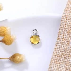 Macro detail of a 6mm amber yellow birthstone pendant with silver metal bezel and bail