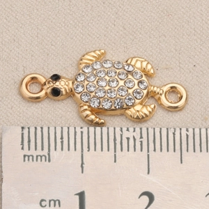 Makroaufnahme von goldener Schildkröte-Schmuckverbinder mit Kristallen und Ösen