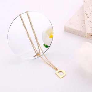 Dettaglio collana in oro con ciondolo lettera D e decorazioni floreali raffinate