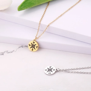 Polished gold and silver stainless steel compass pendant necklaces on white display