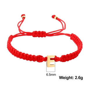 Detail of red braided rope bracelet with golden letter E charm and adjustable pull cords