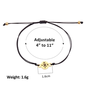 Adjustable black woven rope bracelet with a golden compass pendant on white background