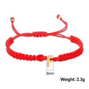 Detail view of red woven bracelet featuring a 6mm golden letter F pendant and adjustable cord