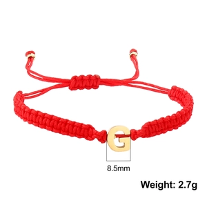 Detail shot of a red woven rope bracelet with a gold letter G pendant and size specs