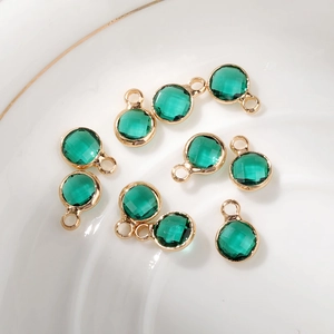Close-up of circular emerald green faceted crystal charms with gold-plated metal frames
