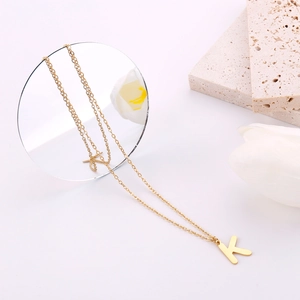 Dettaglio macro della collana con ciondolo lettera K oro su sfondo bianco con tulipano