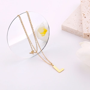 Primo piano della collana con ciondolo lettera L dorata e catenina su pietra naturale