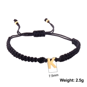 Macro detail of black braided cord bracelet with 7.5mm gold letter K pendant