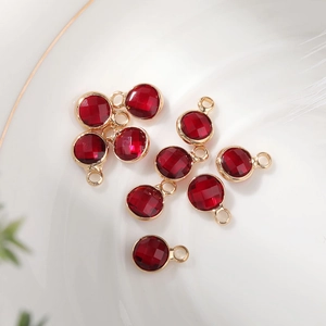 Detailed view of dark red 6mm faceted birthstone pendants with gold hanging loops