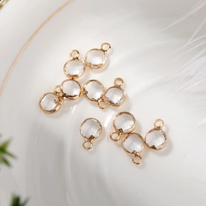 Detailed view of 6mm round crystal glass pendants with gold bezels on a ceramic plate