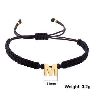 Detail of black braided rope bracelet with gold letter M pendant and weight 3.2g