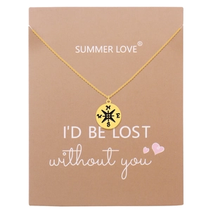 Macro shot of gold compass pendant with N, E, S, W engraving on gift message card