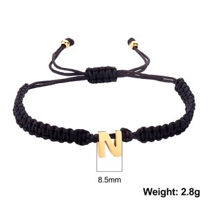 Macro shot of black woven bracelet with golden letter N pendant and dimension specs