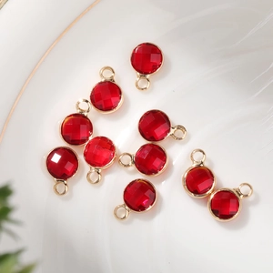 Detailed macro view of 6mm faceted red birthstone pendants with gold-plated copper edges