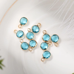 Close-up of blue faceted glass birthstone pendants with gold plated metal rims in 6mm
