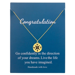 Detail of gold compass pendant on gift card with North West East South engraving