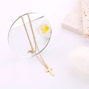Dettaglio della collana con ciondolo a croce dorata minimalista su pietra naturale