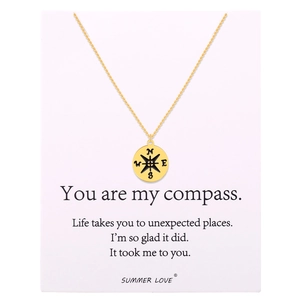 Detail of gold compass pendant on necklace with inspirational message display card