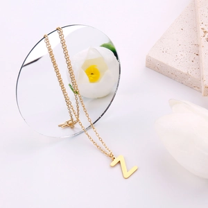 Vista dettagliata di una collana dorata con lettera Z su un vassoio di pietra elegante