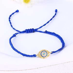 Detail of blue braided rope bracelet with gold evil eye charm and adjustable knot