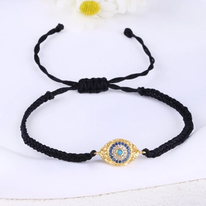 Detailed view of woven black cord bracelet with gold Evil Eye charm and blue crystals