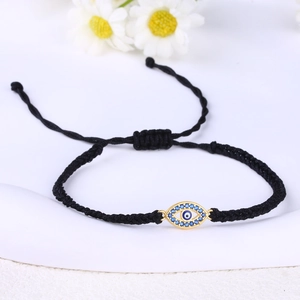Detail of hand-woven black cord bracelet with gold-plated evil eye charm and blue gems