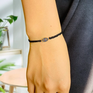Close-up of a woven evil eye bracelet with sparkling crystals on a person's wrist