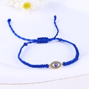Macro shot of blue woven bracelet featuring a gold evil eye charm with zircon accents