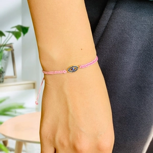 Detail of pink woven evil eye bracelet with sparkling crystals on a female wrist