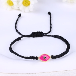 Detail of pink evil eye charm on adjustable black braided cord bracelet with gold plating
