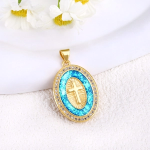 Macro shot of oval gold-plated cross pendant with blue opal effect and zircon halo