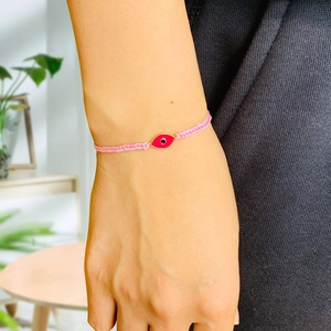 Detailed close-up of pink braided evil eye bracelet with rose gold plated accents