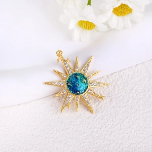 Macro detail of gold starburst pendant featuring blue teal enamel and zircon accents