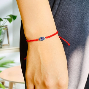 Macro detail of braided red string bracelet with evil eye charm and crystal accents
