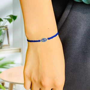 Close-up of hand wearing a blue woven Evil Eye bracelet with blue rhinestone detail