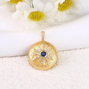 Dettaglio macro del ciondolo a sole dorato con pietra blu e zirconi micro-pavé