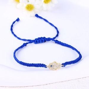 Close-up of blue braided bracelet with gold Hamsa Hand charm and sparkling crystals