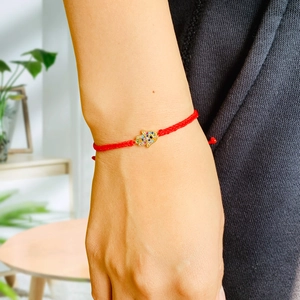 Detail of red braided Hamsa hand bracelet with colorful cubic zirconia and evil eye