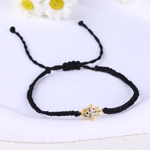 Macro shot of Hamsa hand evil eye charm on black braided cord bracelet with crystals