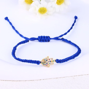 Detail of blue braided bracelet featuring a gold Hamsa hand charm with colorful zircons
