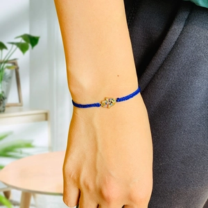 Detailed close-up of a blue braided Hamsa Hand bracelet with colorful rhinestones