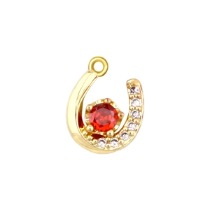 Detail of horseshoe pendant in gold with red zircon center and sparkling side stones